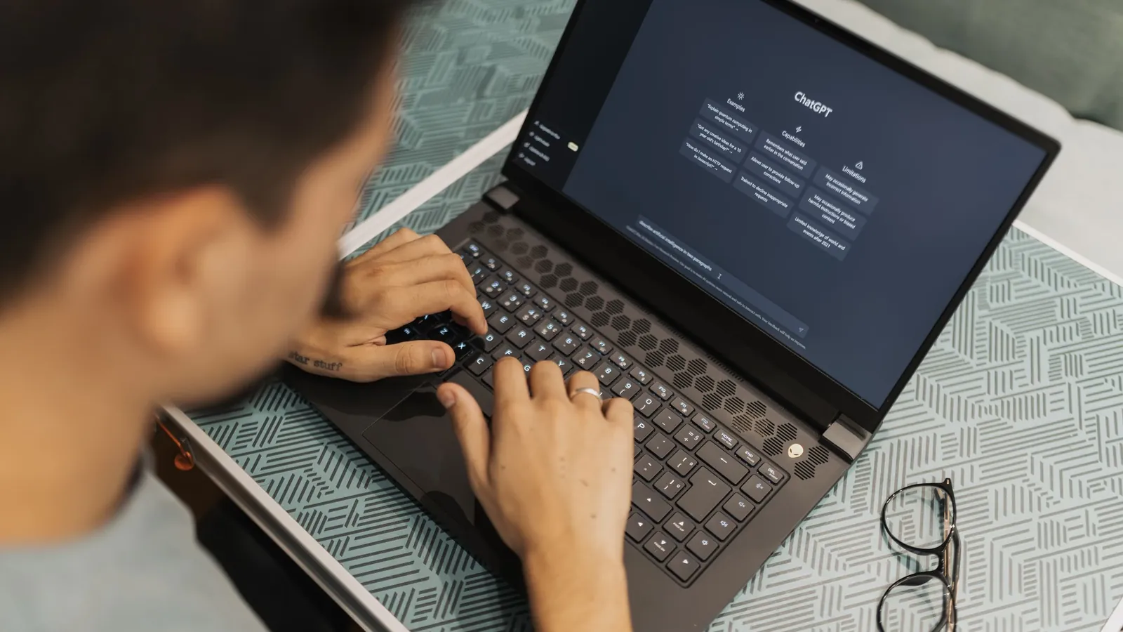 A person typing on a laptop with an AI assistant open on the screen.