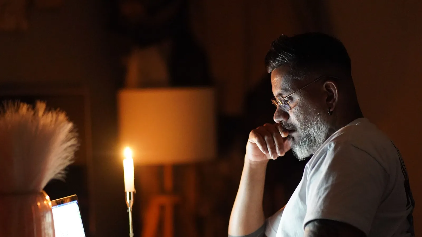 A person working at a laptop late at night in a dimly lit room.